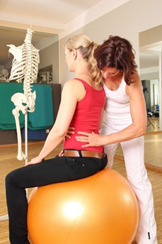 Chiropractor fixing a lady's back on a fit ball