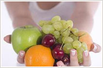 A woman holds an apple, an orange, grapefruit, a peach and some cherries in her hand